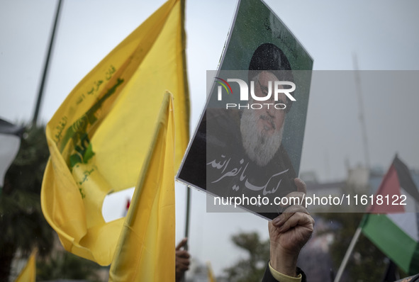 An Iranian protester holds up a portrait of Lebanon's Hezbollah Secretary General, Hassan Nasrallah, during a protest gathering to condemn a...