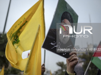 An Iranian protester holds up a portrait of Lebanon's Hezbollah Secretary General, Hassan Nasrallah, during a protest gathering to condemn a...