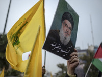 An Iranian protester holds up a portrait of Lebanon's Hezbollah Secretary General, Hassan Nasrallah, during a protest gathering to condemn a...