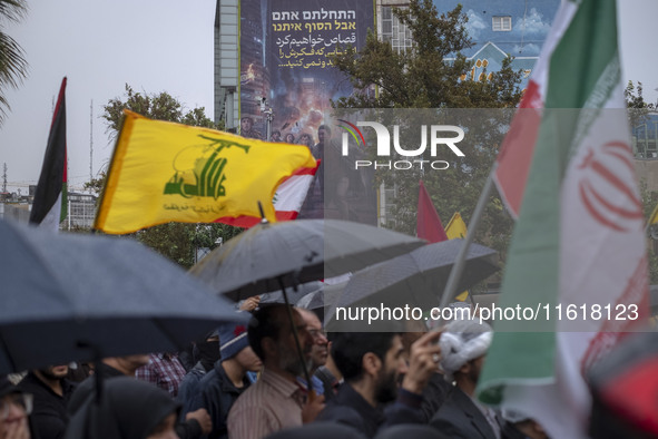 Protesters wave a flag of Lebanon's Hezbollah and an Iranian flag while they gather under an anti-Israeli billboard to condemn an Israeli ai...