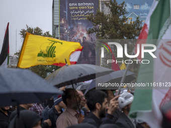 Protesters wave a flag of Lebanon's Hezbollah and an Iranian flag while they gather under an anti-Israeli billboard to condemn an Israeli ai...