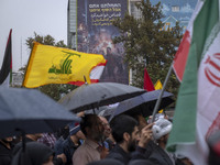 Protesters wave a flag of Lebanon's Hezbollah and an Iranian flag while they gather under an anti-Israeli billboard to condemn an Israeli ai...