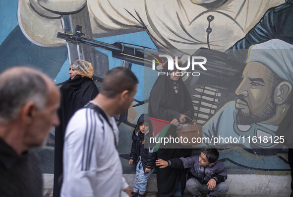 A veiled Iranian protester and her two young sons stand in front of an anti-Israeli mural during a protest gathering to condemn an Israeli a...