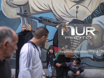 A veiled Iranian protester and her two young sons stand in front of an anti-Israeli mural during a protest gathering to condemn an Israeli a...