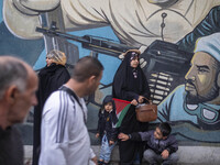 A veiled Iranian protester and her two young sons stand in front of an anti-Israeli mural during a protest gathering to condemn an Israeli a...