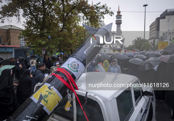 A scaled model of Iran's first ultrasonic missile (Fattah) is carried by a truck during a protest gathering to condemn an Israeli air strike...