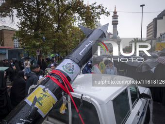 A scaled model of Iran's first ultrasonic missile (Fattah) is carried by a truck during a protest gathering to condemn an Israeli air strike...