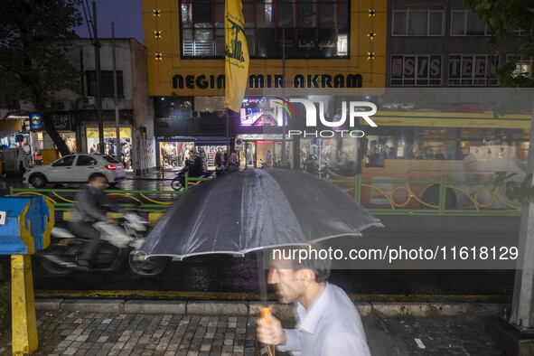 An Iranian man walks past a Hezbollah flag hanging on a sidewalk as a sign of unity with Hezbollah and the Lebanese people in Tehran, Iran,...