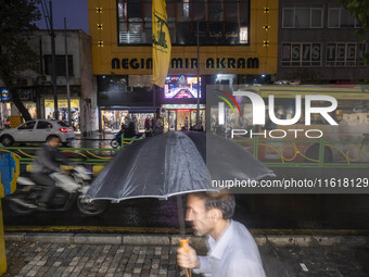 An Iranian man walks past a Hezbollah flag hanging on a sidewalk as a sign of unity with Hezbollah and the Lebanese people in Tehran, Iran,...