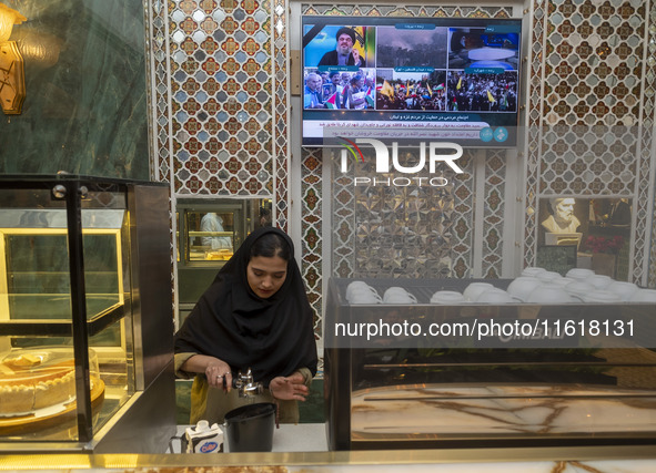 An Iranian female barista works at a cafe, while a portrait of Lebanon's Hezbollah Secretary General, Hassan Nasrallah, who was killed in an...