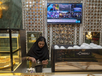 An Iranian female barista works at a cafe, while a portrait of Lebanon's Hezbollah Secretary General, Hassan Nasrallah, who was killed in an...