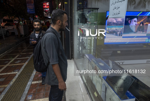 An Iranian man looks at a television featuring a portrait of Lebanon's Hezbollah Secretary General, Hassan Nasrallah, who was killed in an I...