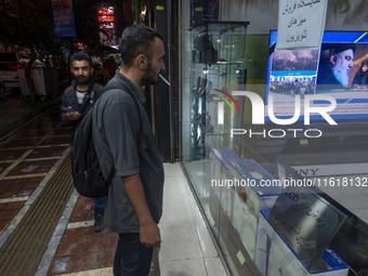 An Iranian man looks at a television featuring a portrait of Lebanon's Hezbollah Secretary General, Hassan Nasrallah, who was killed in an I...