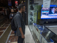 An Iranian man looks at a television featuring a portrait of Lebanon's Hezbollah Secretary General, Hassan Nasrallah, who was killed in an I...