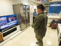 Iranian traders look at a television featuring a portrait of Lebanon's Hezbollah Secretary General, Hassan Nasrallah, who was killed in an I...