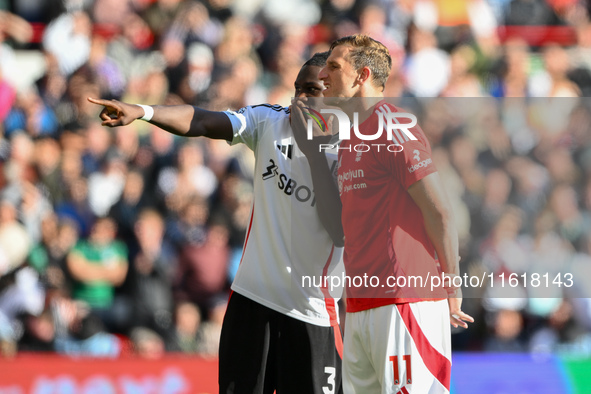 Calvin Bassey of Fulham and Chris Wood of Nottingham Forest look at the VAR screen during the Premier League match between Nottingham Forest...