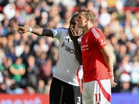 Calvin Bassey of Fulham and Chris Wood of Nottingham Forest look at the VAR screen during the Premier League match between Nottingham Forest...