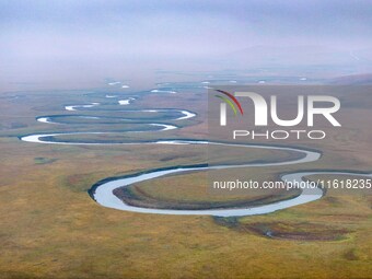 An aerial photo taken in Hulunbuir, China, on September 28, 2024, shows the winding Mogoler River passing through the grassland during autum...