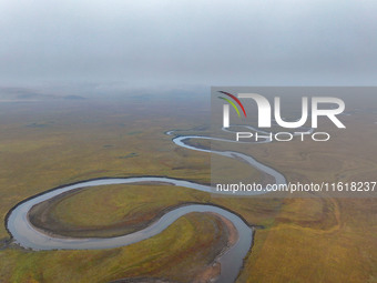 An aerial photo taken in Hulunbuir, China, on September 28, 2024, shows the winding Mogoler River passing through the grassland during autum...