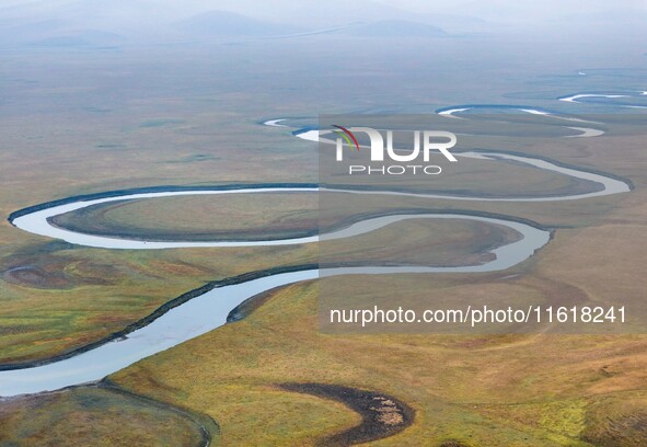 An aerial photo taken in Hulunbuir, China, on September 28, 2024, shows the winding Mogoler River passing through the grassland during autum...