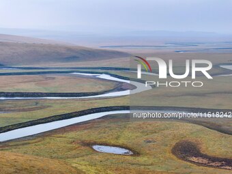 An aerial photo taken in Hulunbuir, China, on September 28, 2024, shows the winding Mogoler River passing through the grassland during autum...