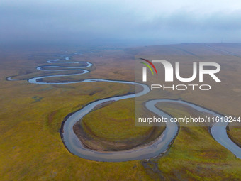 An aerial photo taken in Hulunbuir, China, on September 28, 2024, shows the winding Mogoler River passing through the grassland during autum...