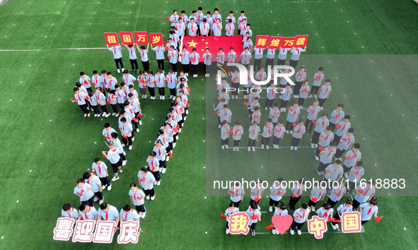 Primary school students pose for a photo with the national flag to celebrate the 75th anniversary of the founding of China in Taicang, Jiang...