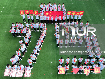 Primary school students pose for a photo with the national flag to celebrate the 75th anniversary of the founding of China in Taicang, Jiang...