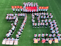 Primary school students pose for a photo with the national flag to celebrate the 75th anniversary of the founding of China in Taicang, Jiang...