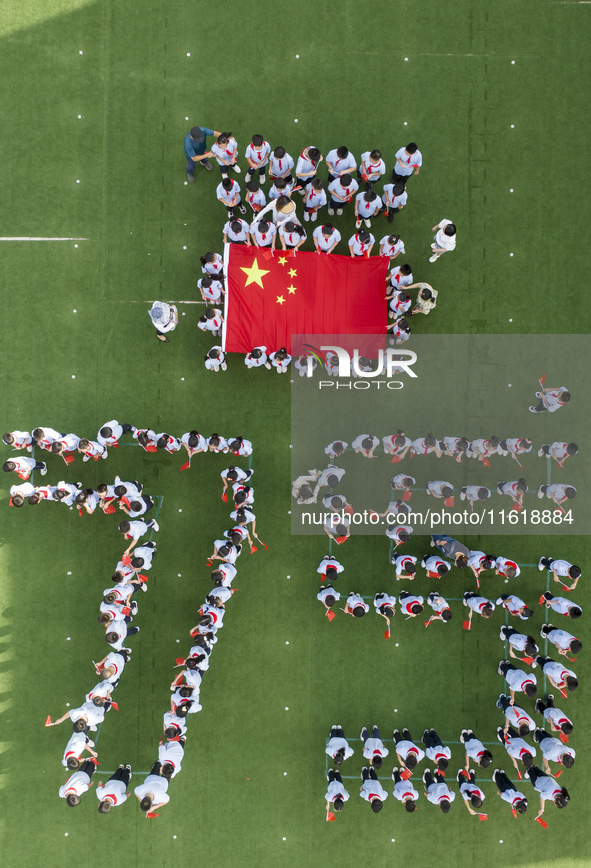 Primary school students pose for a photo with the national flag to celebrate the 75th anniversary of the founding of China in Taicang, Jiang...