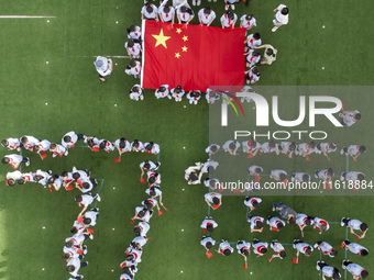 Primary school students pose for a photo with the national flag to celebrate the 75th anniversary of the founding of China in Taicang, Jiang...