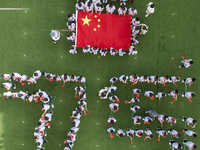 Primary school students pose for a photo with the national flag to celebrate the 75th anniversary of the founding of China in Taicang, Jiang...