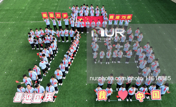 Primary school students pose for a photo with the national flag to celebrate the 75th anniversary of the founding of China in Taicang, Jiang...