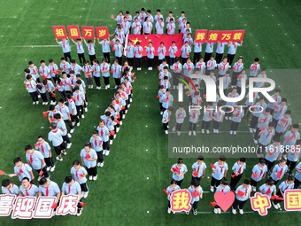 Primary school students pose for a photo with the national flag to celebrate the 75th anniversary of the founding of China in Taicang, Jiang...