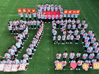 Primary school students pose for a photo with the national flag to celebrate the 75th anniversary of the founding of China in Taicang, Jiang...