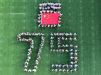 Primary school students pose for a photo with the national flag to celebrate the 75th anniversary of the founding of China in Taicang, Jiang...