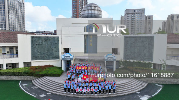 Primary school students pose for a photo with the national flag to celebrate the 75th anniversary of the founding of China in Taicang, Jiang...