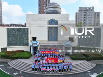 Primary school students pose for a photo with the national flag to celebrate the 75th anniversary of the founding of China in Taicang, Jiang...