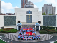 Primary school students pose for a photo with the national flag to celebrate the 75th anniversary of the founding of China in Taicang, Jiang...