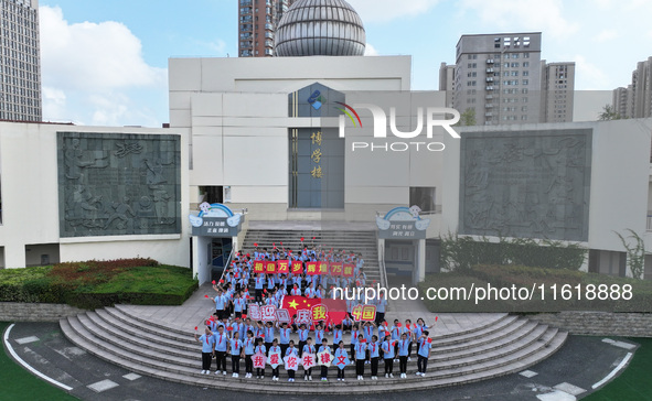 Primary school students pose for a photo with the national flag to celebrate the 75th anniversary of the founding of China in Taicang, Jiang...