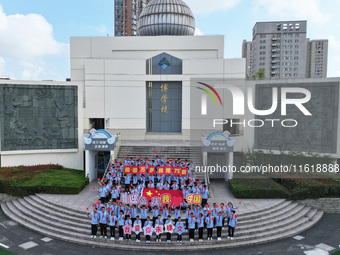 Primary school students pose for a photo with the national flag to celebrate the 75th anniversary of the founding of China in Taicang, Jiang...