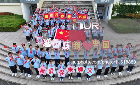 Primary school students pose for a photo with the national flag to celebrate the 75th anniversary of the founding of China in Taicang, Jiang...