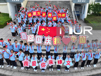 Primary school students pose for a photo with the national flag to celebrate the 75th anniversary of the founding of China in Taicang, Jiang...