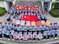 Primary school students pose for a photo with the national flag to celebrate the 75th anniversary of the founding of China in Taicang, Jiang...