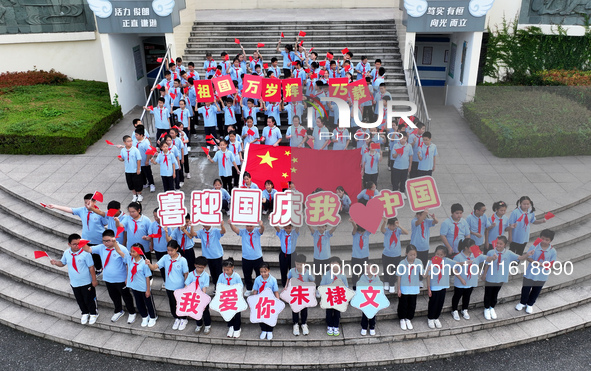 Primary school students pose for a photo with the national flag to celebrate the 75th anniversary of the founding of China in Taicang, Jiang...