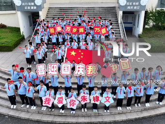 Primary school students pose for a photo with the national flag to celebrate the 75th anniversary of the founding of China in Taicang, Jiang...