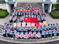 Primary school students pose for a photo with the national flag to celebrate the 75th anniversary of the founding of China in Taicang, Jiang...