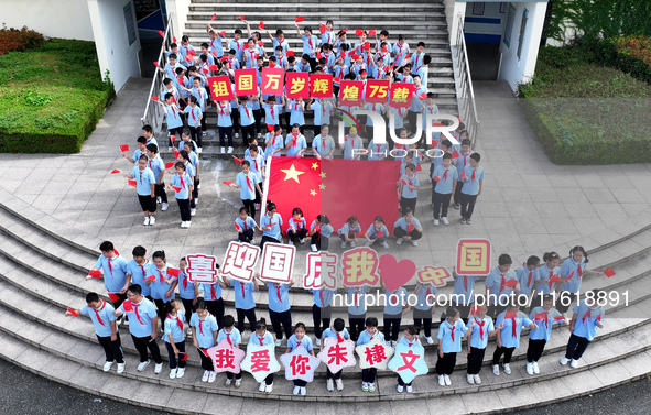 Primary school students pose for a photo with the national flag to celebrate the 75th anniversary of the founding of China in Taicang, Jiang...