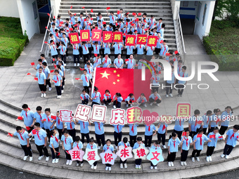 Primary school students pose for a photo with the national flag to celebrate the 75th anniversary of the founding of China in Taicang, Jiang...