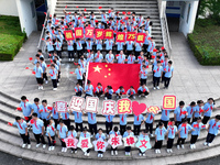 Primary school students pose for a photo with the national flag to celebrate the 75th anniversary of the founding of China in Taicang, Jiang...